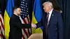 Trump und Selenskyj schütteln sich in Davos vor US- und Ukraine-Flaggen die Hand.