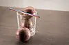 Drei Passionsfrüchte in einem Glas, eine davon mit Strohhalm auf einem Tisch.
