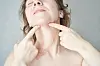 Frau mit Neck-Taping an Hals und Kinn zeigt Hautstraffung in Nahaufnahme.