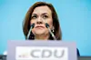 Frau hinter CDU-Pult mit zwei Mikrofonen vor blauem Hintergrund.