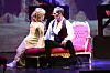 Deborah Sasson und Axel Olzinger spielen in „Das Phantom der Oper“ auf einem roten Sofa auf der Bühne.
