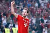 Harry Kane jubelt im roten FC-Bayern-Trikot mit erhobener Faust vor den Fans in Berlin.