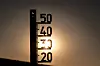 Außenthermometer vor tief stehender Sonne, Symbol für sommerliche Hitze.