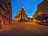 Chilehaus in Hamburg bei Dämmerung, beleuchtete Fassade vor blauem Himmel und leerer Straße.