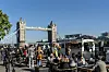 Menschen sitzen an Tischen vor Imbisswagen nahe der Tower Bridge in London.