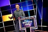 Fabian Köster steht im Studio vor dem Pult der Quizshow „Das Fifty-Fifty-Quiz“.