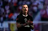 Jackson Irvine von St. Pauli im schwarzen Trikot auf dem Spielfeld, Hände vor der Brust.