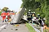 Rettungskräfte neben umgestürztem Anhänger und Trümmern auf einer Landstraße