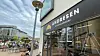 Andresen-Filiale an Straßenecke mit Schaufenster, draußen Café-Tische und Passanten.
