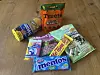 Bunte Süßigkeiten- und Snackpackungen auf einem Holzboden, darunter Mentos, Treets und Katjes.