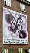 Großes Banner an Backsteingebäude mit „Graduate Show 2026“ und „No Speeches, Just Art!“