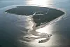 Grün bewachsene Insel mit Sandbänken in glitzerndem Wasser aus der Luft.