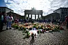 Menschen legen Blumen, Flaggen und Kerzen vor dem Brandenburger Tor nieder.