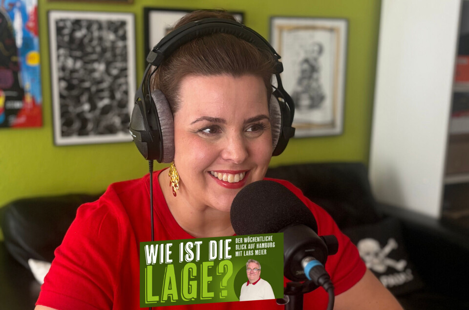 Frau mit Kopfhörern spricht ins Mikrofon und hält ein Magazin mit „WIE IST DIE LAGE?“