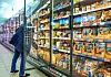 Mann vor gekühlten Supermarktregalen in der Fischabteilung mit Fischprodukten.
