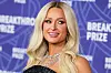 Paris Hilton lächelt vor einer violetten „Breakthrough Prize“-Wand mit mehrreihigem Schmuck.