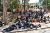 Migranten ruhen vor dem CETI in Ceuta aus, im Hintergrund stehen weitere Menschen an einer Treppe.