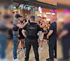 Polizeibeamte stehen in einem Einkaufszentrum vor McCafé und Dunkin' Donuts; Passanten beobachten die Szene.