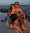 Paar sitzt auf dem Deck einer Yacht vor dem Meer bei Sonnenuntergang.