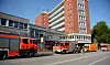 Mehrere Feuerwehrfahrzeuge stehen vor einem Wohn- und Geschäftshaus an einer Straße.