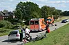 Rettungskräfte sichern Unfallstelle mit Auto, Rettungswagen und Hubschrauber an einer Landstraße.