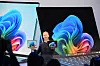 Brett Ostrum zeigt Surface-Notebook und Tablet vor großen Windows-Displays für KI-PCs.