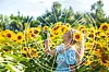 Frau im Sonnenblumenfeld zwischen gelben Blüten im Sonnenlicht.