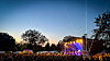 Menschenmenge vor beleuchteter Open-Air-Bühne bei Sonnenuntergang