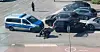 Polizeifahrzeuge und Motorrad an Unfallstelle auf Parkplatz, ein Beamter kniet am Boden.