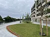Kurviger Uferweg neben moderner Wohnanlage mit Rasen, Bäumen und Zaun am Wasser
