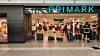 Primark-Ladeneingang mit Kleidungsgestellen und Kunden im Einkaufszentrum.