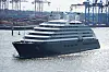 Große Luxusyacht auf dem Wasser vor Hafenkränen und Industrieanlagen.