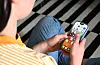 Jugendliche sitzt auf dem Boden und bedient ein Smartphone mit App-Symbolen auf dem Display.