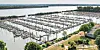 Weitläufige Marina mit vielen leeren Bootsanlegern an ruhigem Wasser und grünen Uferanlagen.