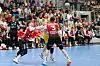 Lukas Schneider von HSG Krefeld Niederrhein dribbelt gegen zwei Nordhorn-Lingen-Spieler vor voller Tribüne.