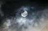 Mond bedeckt bei partieller Sonnenfinsternis die Sonne über dem Hamburger Stadtpark, Wolken ziehen vorbei.