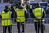 Security-Mitarbeiter in gelben Warnwesten sichern den Zugweg des Rosenmontagszugs in Düsseldorf.