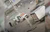 Hund auf staubiger Straße zwischen geparkten Fahrzeugen und einfachen Unterständen in einem Wohngebiet.