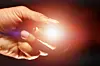 Hand hält einen Laserpointer mit rotem Lichtstrahl.