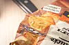 Geöffnete Chipstüte wird mit einer Flamme an der Oberkante verschweißt.