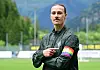 Jackson Irvine steht im FC-St.-Pauli-Trikot auf dem Trainingsplatz und zeigt auf seine Regenbogen-Armbinde.