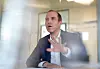 Dennis Thering spricht im dpa-Interview und hebt die Hand in einem Büro.
