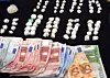 Kokainkugeln, Bargeld und Euro-Scheine auf schwarzer Unterlage bei einer Durchsuchung