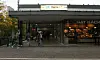 Eingang zum U-Bahnhof Berne in Hamburg, mehrere Passanten vor dem Glasbau.