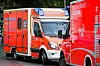 Zwei rote Rettungswagen stehen dicht nebeneinander auf einer Straße.