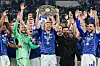 Edin Dzeko hebt die Trophäe, Schalke-Spieler und Trainer jubeln in der Veltins-Arena.