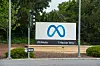 Meta-Logo nahe der Konzernzentrale in Menlo Park, daneben Straße, Verkehrszeichen und Bäume.