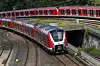 S-Bahn der Deutschen Bahn fährt vor dem Hamburger Hauptbahnhof auf dem Gleis, im Hintergrund ein weiterer Zug.