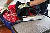 Zollbeamter durchsucht am Ostseekai einen Koffer mit Kleidung und Taschen.