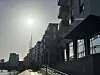 Sonne brennt auf Neubauten in der Hamburger HafenCity an einer leeren Promenade.
